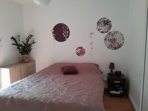 Une chambre à coucher avec un lit, une table de chevet, une lampe et une plante en pot.
