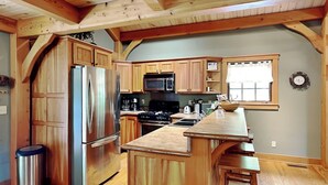 Una cocina con armarios de madera, electrodomésticos de acero inoxidable, una isla central y un reloj en la pared.