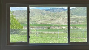 Uma janela com vista para colinas ondulantes e uma cordilheira distante.