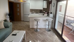 A modern kitchen with white cabinets, a central island, and a dining area with two bar stools.