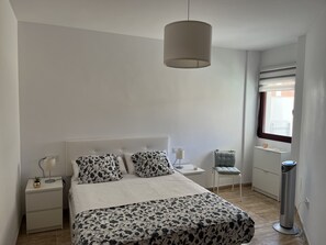 Relax in a serene bedroom with a neatly made bed, bedside table, and chair by the window.