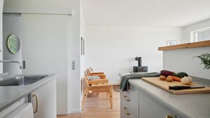 Een moderne keuken met een inbouwfornuis, een houten eettafel en een snijplank met groenten.