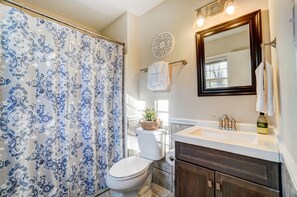 Une salle de bain équipée d’un rideau de douche, de toilettes, d’un lavabo et d’un meuble-lavabo.