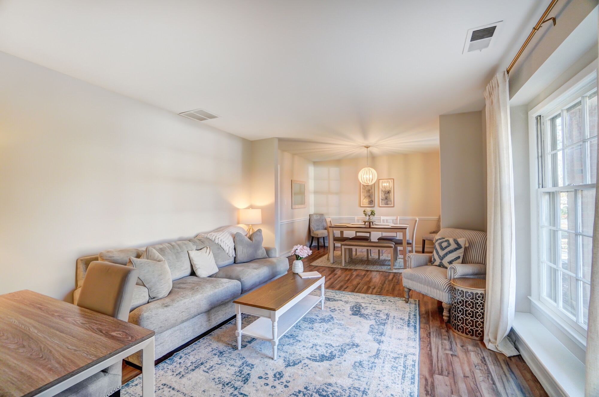 A living room with a sofa, coffee table, and dining area with chairs and a table.