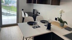 A modern dining area with a table set for two, a potted orchid, and a view of the outside. - Luxury 2023 Flat -Center Terrace Parking (Luxembourg City)