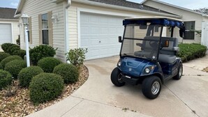 A residential house with a garage, a driveway, and a golf cart parked in front. - 3 bedroom / 2 bath Courtyard Villa w/ cart! (The Villages)
