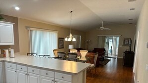 A spacious kitchen with a large island, white cabinetry, and a dining area with a table and chairs. - 3 bedroom / 2 bath Courtyard Villa w/ cart! (The Villages)