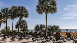 A beachside lounge area with rows of sun loungers and palm trees, a sign indicating 'KEEP OFF DANGER', and a view of the ocean. - Modern*Oceanfront2BR*Pools*Downtown*HoneymoonSuite (Myrtle beach)