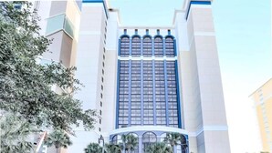 A hotel with a central atrium, palm trees, and a sign reading "THE E". - Modern*Oceanfront2BR*Pools*Downtown*HoneymoonSuite (Myrtle beach)