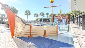 A water park with a wave-shaped slide, a water fountain, and a pool area. - Modern*Oceanfront2BR*Pools*Downtown*HoneymoonSuite (Myrtle beach)