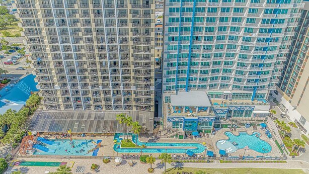 A high-rise hotel with multiple balconies, a pool area with various water features, and a landscaped garden. - Modern*Oceanfront2BR*Pools*Downtown*HoneymoonSuite (Myrtle beach)