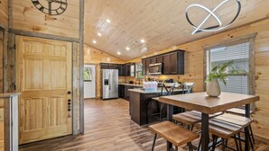 Eine moderne Küche mit Holzschränken, einem Edelstahlkühlschrank und einem Holzesstisch mit Bänken.