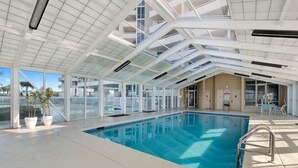 An indoor swimming pool with a high ceiling and large windows. - Coastal Elegance Beachfront View (Pensacola)