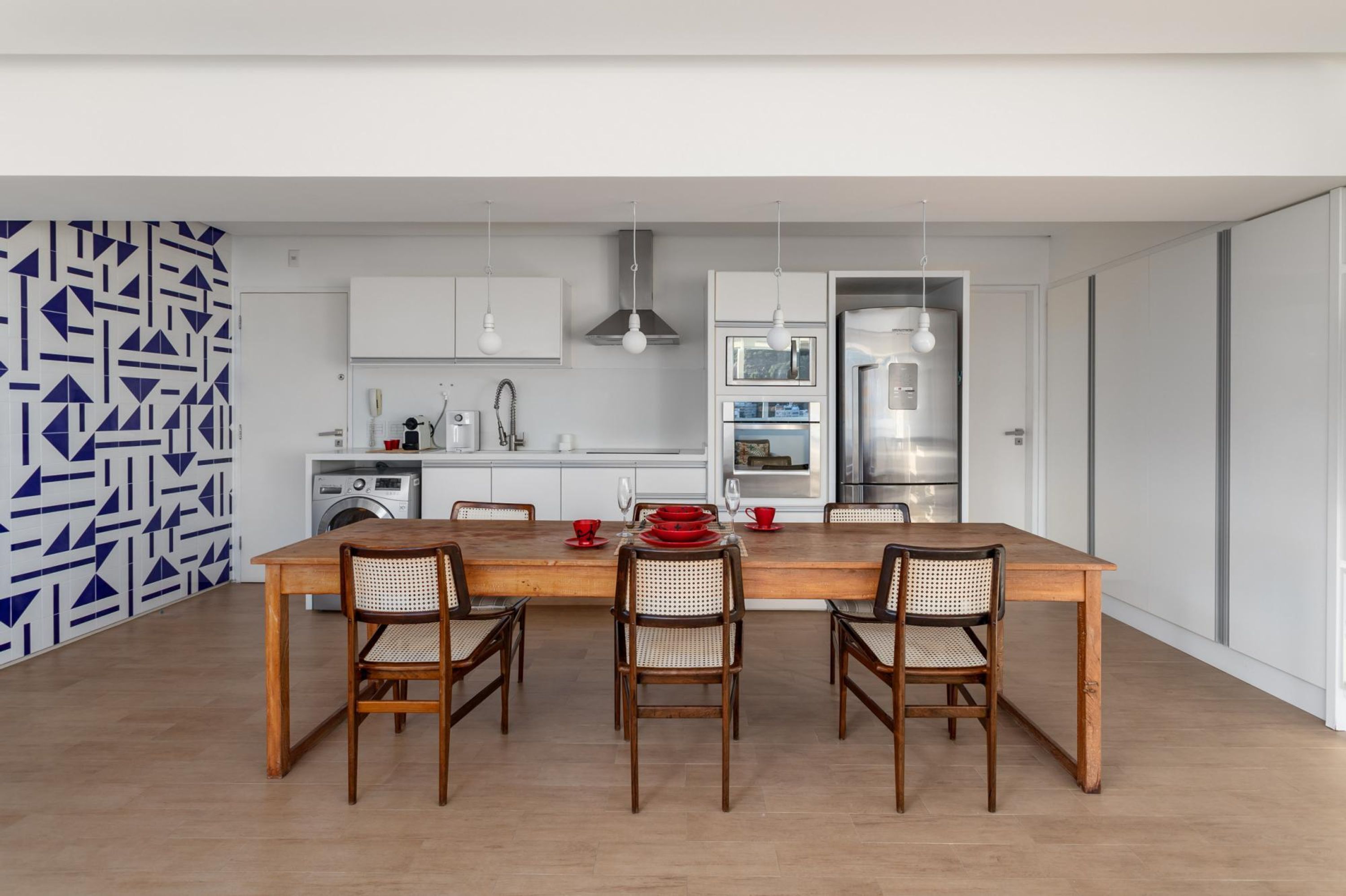 A modern kitchen with white cabinets, a wooden dining table, and wicker chairs.