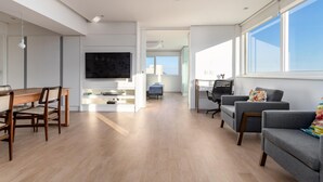 A spacious living area with a wooden dining table, grey sofas, and a large TV. - Nice in Leblon View to Morro 2 irm os Guc6 ZN1 (Rio de Janeiro)