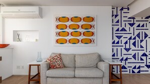 A modern living room with a grey sofa, a small side table, and a wall-mounted air conditioner. - Nice in Leblon View to Morro 2 irm os Guc6 ZN1 (Rio de Janeiro)