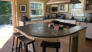 A kitchen with a large island, white cabinets, and a view of the outdoors.