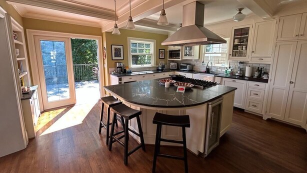 A spacious kitchen with a large island, pendant lighting, and a view to a balcony.