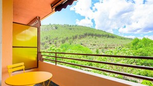 A balcony with a yellow table and chair, a view of a green landscape with trees and hills, and a clear sky. - A homely place with views in Jerica (Jérica)
