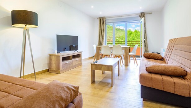 A modern living room with a flat-screen TV, a sofa, a coffee table, and a dining area with chairs. - A homely place with views in Jerica (Jérica)