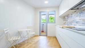 A compact kitchen with white cabinets, a wooden countertop, and a window with a view of greenery. - A homely place with views in Jerica (Jérica)