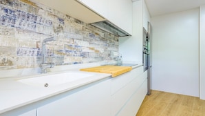 A modern kitchen with a white countertop, a wooden cutting board, a stainless steel sink, and a backsplash with a mosaic tile design. - A homely place with views in Jerica (Jérica)