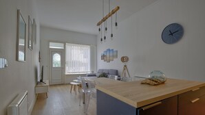 A modern kitchen with a wooden countertop, a dining area with a table and chairs, and a living room with a sofa. - Boulevard de la Plage flat-Arcachon (Arcachon)
