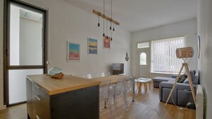 A modern living room with a wooden dining table, clear plastic chairs, a grey sofa, and a wooden floor. - Boulevard de la Plage flat-Arcachon (Arcachon)