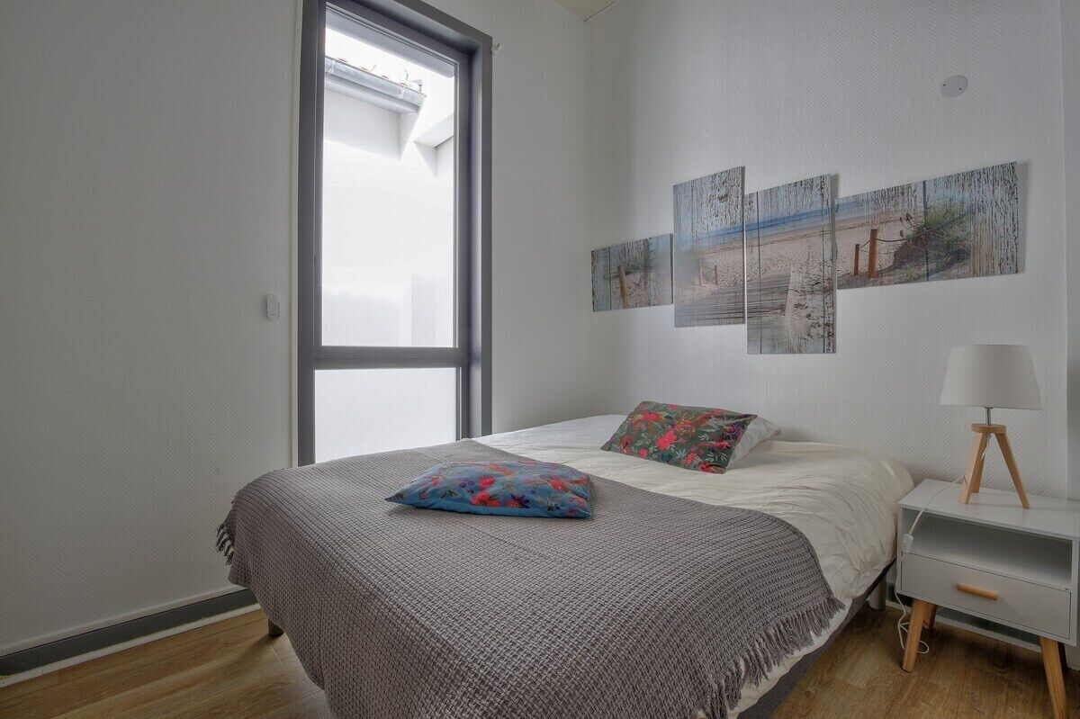 Une chambre à coucher avec un lit, une table de chevet, une lampe et des œuvres d’art murales.