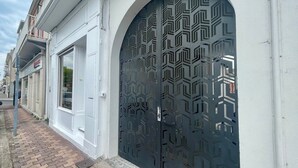 A building facade with a large arched window and a geometric patterned door. - Boulevard de la Plage flat-Arcachon (Arcachon)