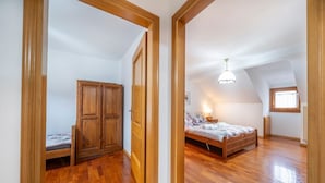 A bedroom with a wooden wardrobe, a bed, and a sloped ceiling with a window. - GuestHost - Penthouse Central Apartment (Tarvisio)