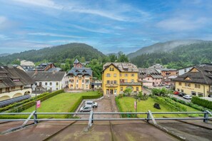 A town with traditional buildings, a central yellow building, and a view of green hills. - GuestHost - Penthouse Central Apartment (Tarvisio)