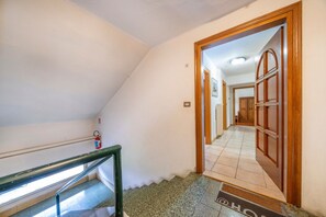 A staircase with a metal handrail, a fire extinguisher on the wall, and a door leading to another room.