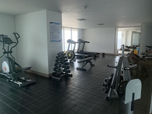 A gym with exercise equipment like treadmills, an elliptical, and dumbbells. - Home Beach in Palmetto Sunset (Cartagena)