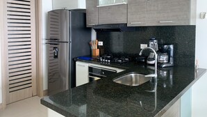 Eine moderne Küche mit einem Edelstahlkühlschrank, einem Gasherd und einer Kaffeemaschine.
