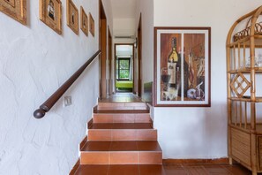 Un escalier avec une rampe en bois, un mur orné de tableaux encadrés et une grande œuvre d’art encadrée représentant des bouteilles et des verres.