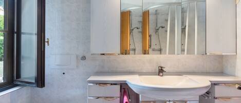 Un baño moderno con inodoro, lavamanos, espejo y ducha.