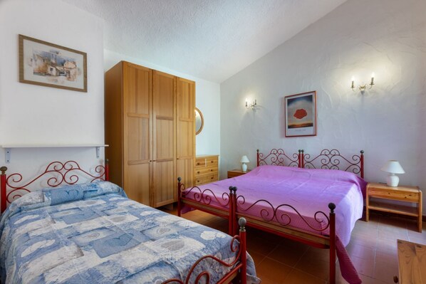 Ein Schlafzimmer mit zwei Betten, einem Holzschrank, Wandleuchten und Kunstwerken.