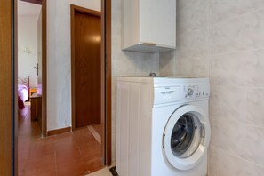 Un espace buanderie comprenant un lave-linge, une porte en bois et un mur carrelé.