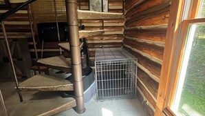 Una scala a chiocciola all'interno di una baita di legno, con una gabbia metallica al piano inferiore.