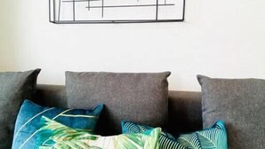 A room with a grey sofa set, a large abstract artwork on the wall, and tropical patterned pillows. - Spac. Flat -Kirchberg w Parking&Terrace (Luxembourg City)