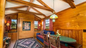 L’intérieur d’un chalet chaleureux, avec une table à manger en bois, un canapé bleu et un tapis à motifs.