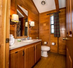 Ein Badezimmer aus Holz mit einem großen Spiegel, einem Waschbecken und einer Toilette.
