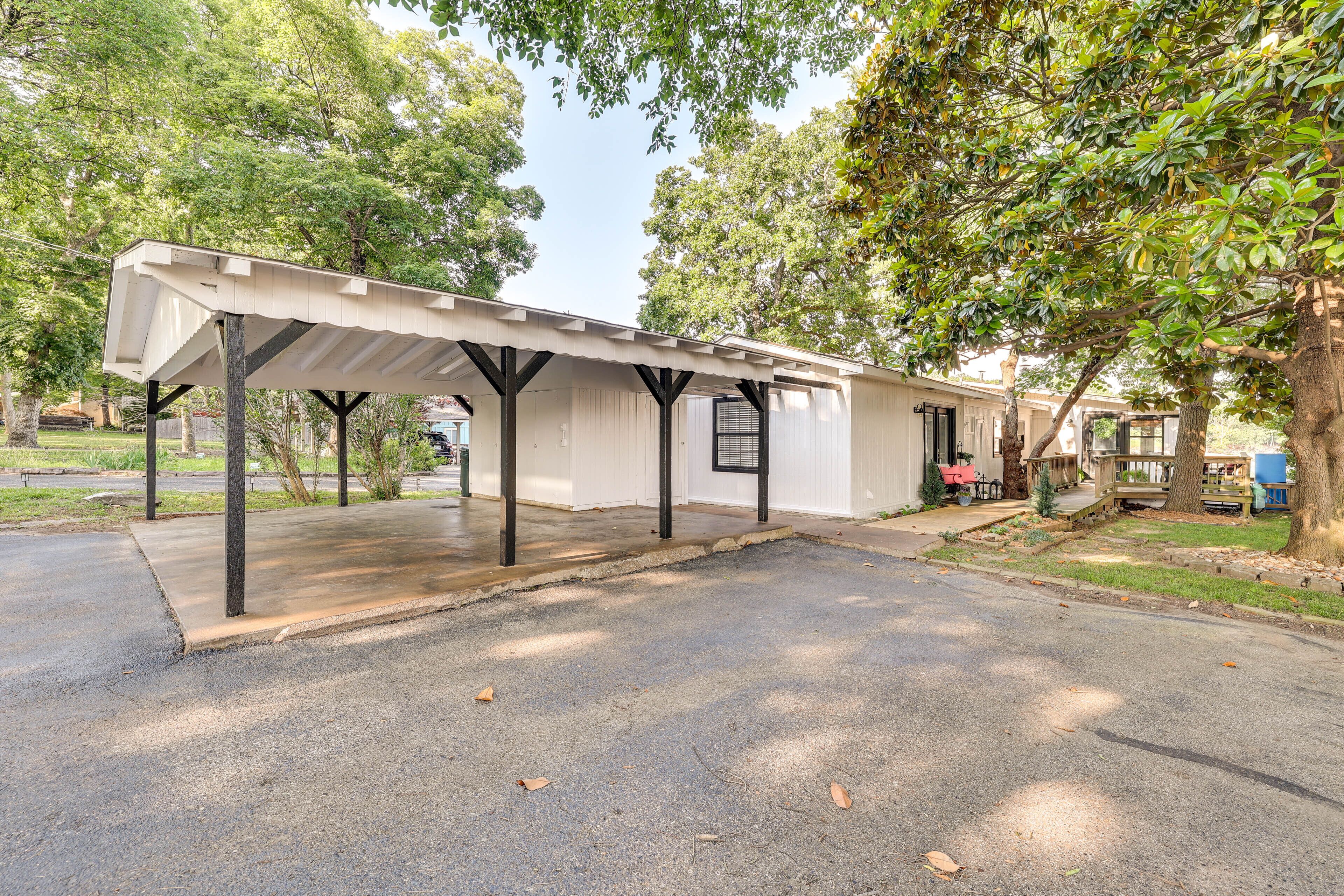 A covered outdoor area with a concrete floor, surrounded by trees.