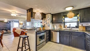 A modern kitchen with dark cabinets, stainless steel appliances, and a central island. - Waterfront Home w/ Dock in South Grand Lake! (Vinita)