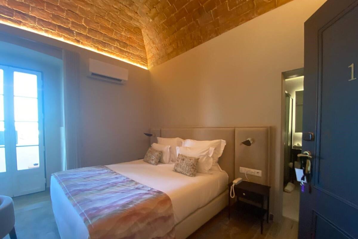 A bedroom with a bed, bedside table, and a door with a number.
