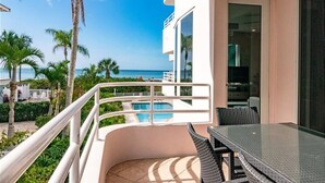 A balcony with a pool, outdoor furniture, and a view of the ocean.