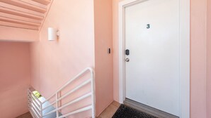 A hallway with a white door marked with the number 3, a white railing, and a small window.