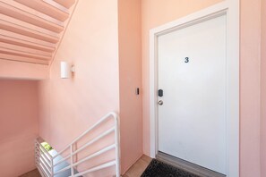 A hallway with a white door marked with the number 3, a white railing, and a small window. - Beachfront Condo on AMI (Holmes Beach)
