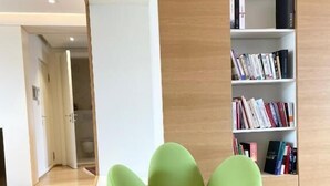A modern interior with a green, flower-shaped seating area, a wooden bookshelf, and a wooden floor.